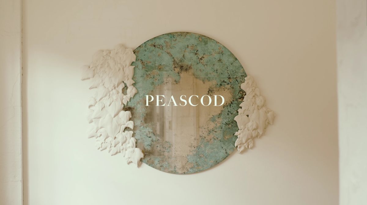 Luxury mirror with sculpted ivy and verdigris reflective glass overlaid with the Peascod logo.