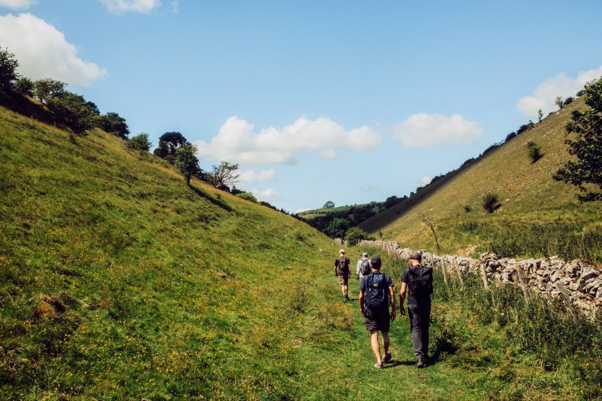 A few men walking up the bottom of a green valley.