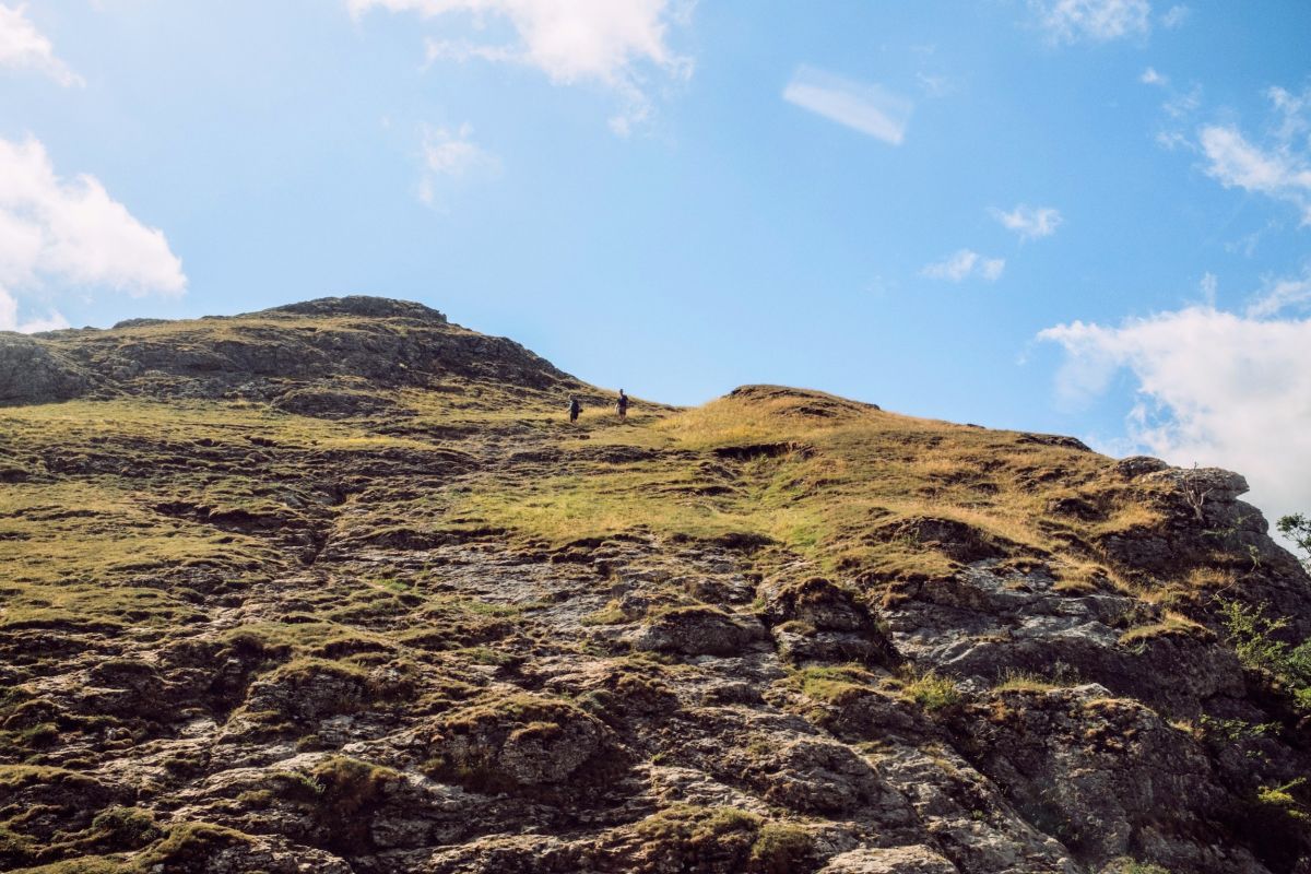 Two people coming down a steep, rocky hill.