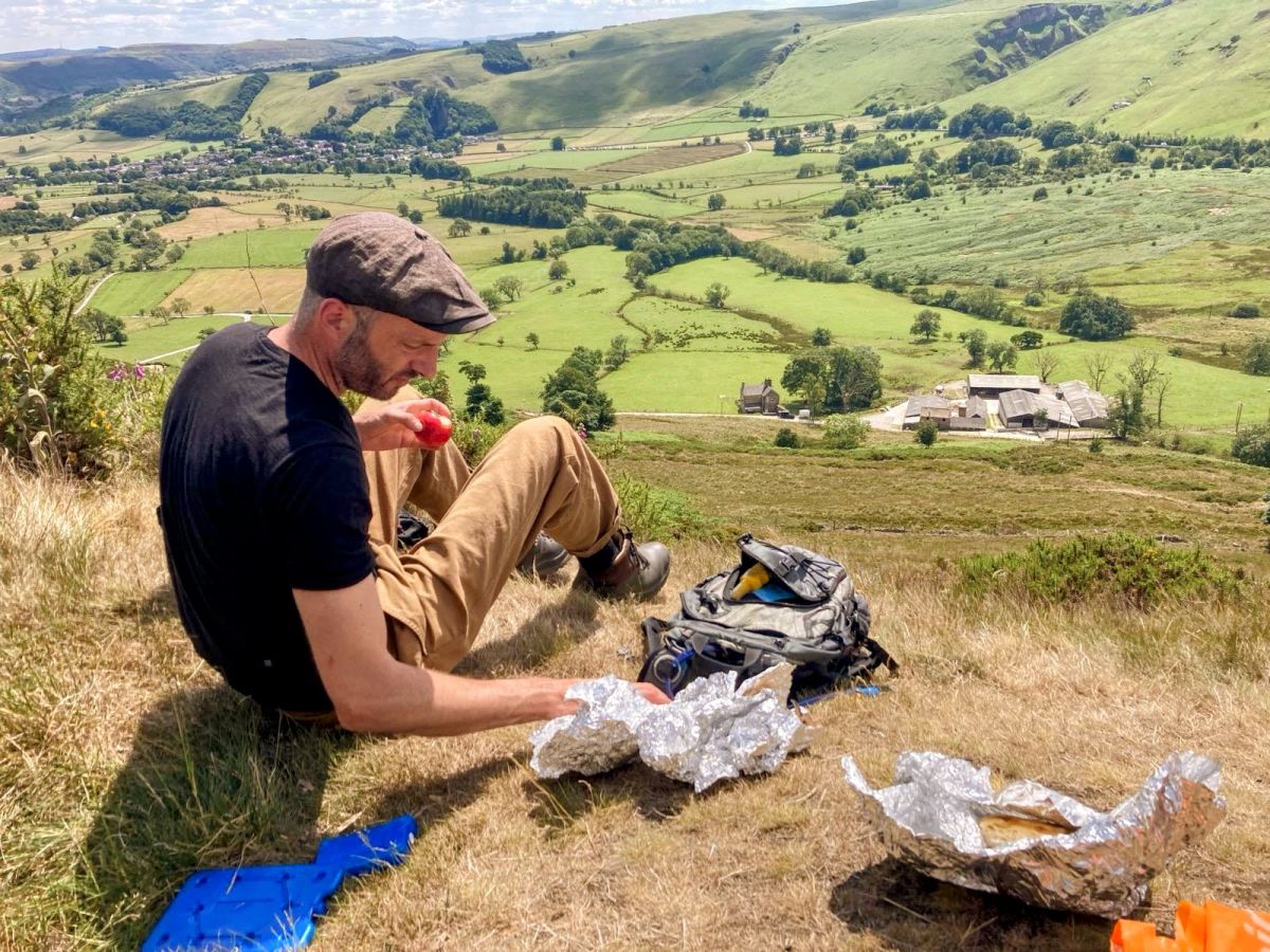 Man sitting and eating with a view over a lush, green valley.